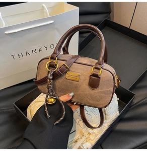 Detailed view of brown textured crossbody bag with gold hardware in premium gift packaging