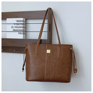 Detail view of deep brown vintage leather tote bag with side drawstring and golden square buckle