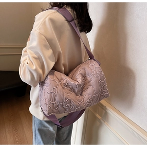 Detailed back view of a lavender quilted shoulder bag with floral embroidery on model
