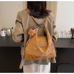Detailed view of the brown leather tote with fashion lettering and cute bear charm