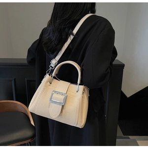 Detail of minimalist beige bucket bag featuring silver buckle and adjustable shoulder strap
