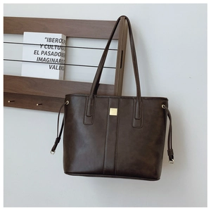 Detail of dark brown leather tote bag with golden hardware and drawstring on wooden hanger