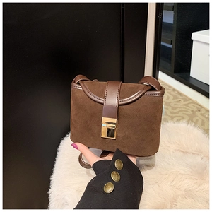 Detailed close-up of dark brown frosted suede texture and gold metal buckle on handbag
