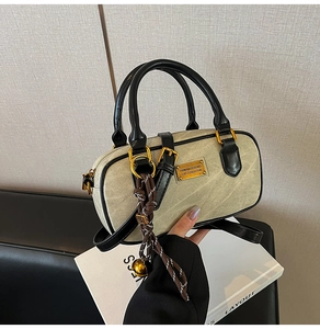 Detail of canvas mini Boston bag with black leather trim and decorative charm
