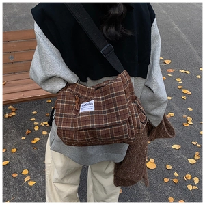 Detailed view of brown plaid messenger bag with adjustable strap on autumn street