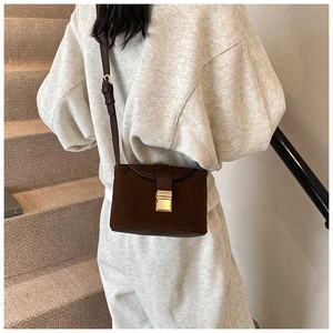 Detail of vintage matte crossbody bucket bag with golden metal buckle and shoulder strap
