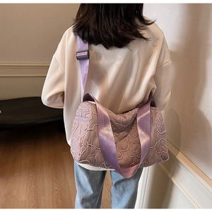 Rear view of model wearing a purple quilted crossbody canvas bag with adjustable strap