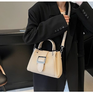 Chic beige bucket bag detail featuring a large square silver metal buckle and top handle