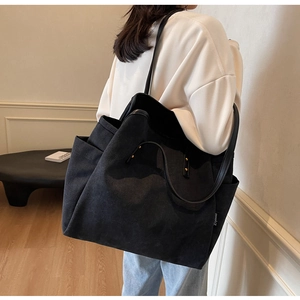 Detail of black canvas tote bag showing side metal rivets and stylish leather straps