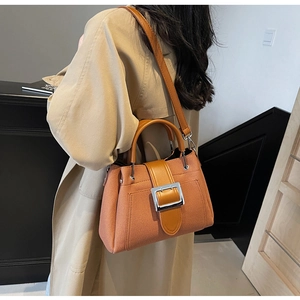 Detail of orange bucket bag with textured fabric and large silver metal buckle strap