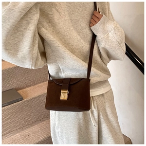 Detail of vintage matte brown crossbody bag with gold metal buckle on a shoulder strap