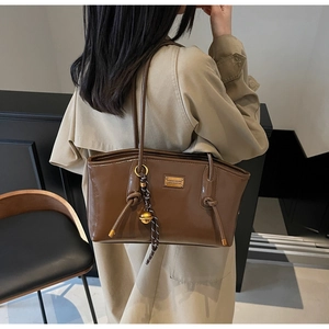 Detail of dark brown oil wax leather tote bag featuring gold nameplate and knot handle