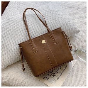 Detail of dark brown leather tote bag with gold metal hardware and vertical embossed texture