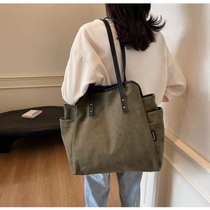 Detail of army green canvas tote bag with black leather handle and metal rivet
