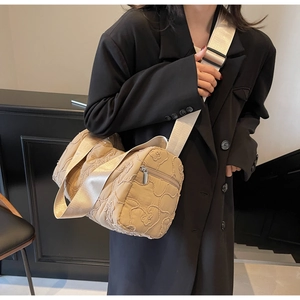 Detail of light khaki quilted crossbody bag with adjustable wide strap on model