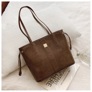 Detail of dark brown tote bag with matte texture and decorative gold square buckle