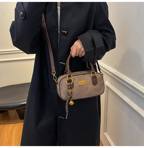 Detail view of brown textured crossbody bag with gold hardware and silk ribbon on model