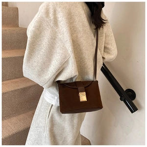 Detail of vintage brown suede crossbody bag with gold buckle on casual outfit