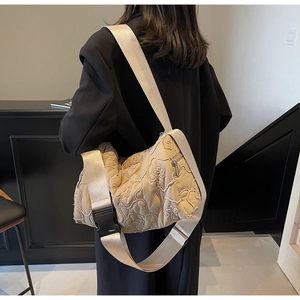 Detail of beige quilted crossbody bag featuring textured 3D cloud floral embroidery