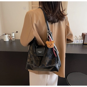 Detail of large tote bag with brown marble texture and plush bear charm on model