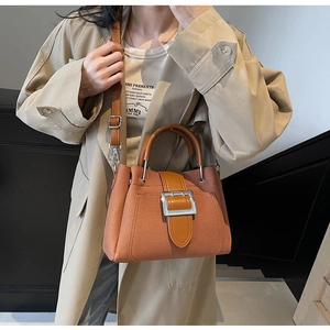 Detail of caramel bucket bag featuring silver square buckle and textured synthetic leather