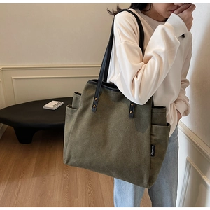 Olive green canvas tote bag featuring side pockets and elegant slim shoulder straps