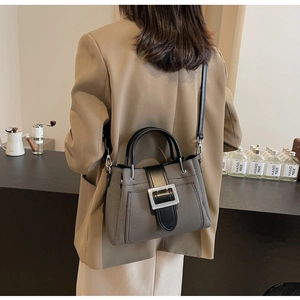 Detail view of the gray textured fabric shoulder bag with metallic buckle on a model