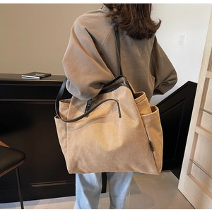 Detail of khaki canvas tote bag with black leather trim and gold rivet hardware
