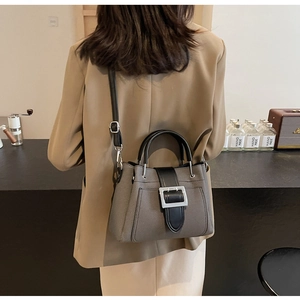 Fashionable grey-brown bucket bag with leather handles shown in a cafe setting