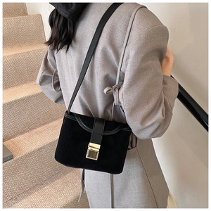 Detail of black crossbody bag with textured suede material and golden metal buckle