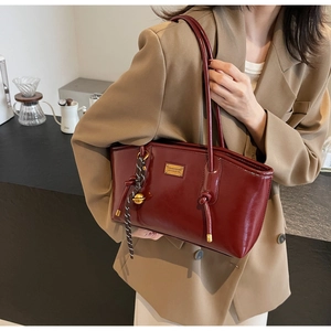 Close-up of wine red oil wax leather shoulder bag with golden metal logo and charm