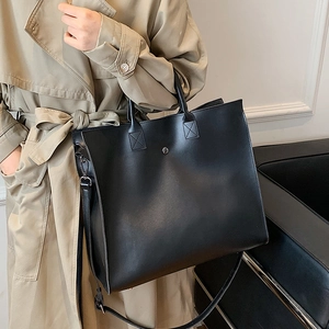 Large black matte leather tote bag with handles and adjustable shoulder strap for work