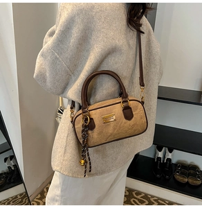 Detail showing vintage brown crossbody boston bag with contrast straps and metal tag