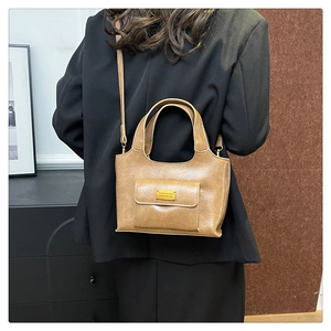 Détail du sac seau en cuir PU caramel avec logo en métal doré et poche avant à rabat