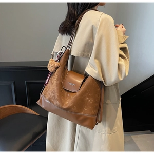 Detail of a brown leather tote bag with contrast stitching and decorative scarf on a model