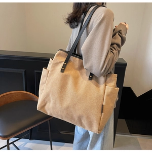 Detail view of khaki canvas tote bag featuring reinforced black straps and side pockets