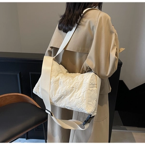 Detail of off-white canvas pillow bag with floral quilting and wide shoulder strap