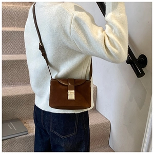 Detail of vintage brown frosted crossbody bucket bag with golden buckle on a model