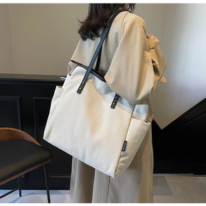 Detail of canvas tote bag with side pockets and black shoulder straps in interior setting