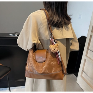 Detail of caramel brown hobo tote bag with plush bear charm and plaid scarf accessory