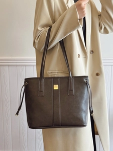 Vintage dark brown tote bag with gold logo plaque and minimalist stitching detail