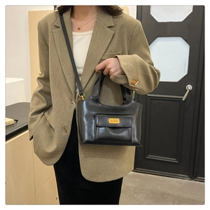 Détail d'un sac seau vintage en cuir PU noir avec plaque dorée et bandoulière réglable