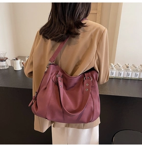 Détail du sac cabas en cuir marron rouge montrant les rivets métalliques et la texture