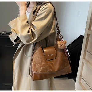 Brown leather hobo bag detail with plush bear charm and Fashion & Bags lettering
