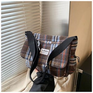 Detail of vintage plaid messenger bag with black wide strap and woven logo label