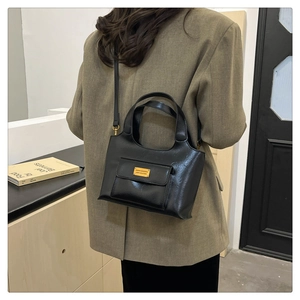Vue arrière d'un mannequin portant un sac à main noir mat avec plaque logo dorée élégante