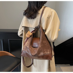 Brown vintage tote bag with plush bear charm and silk scarf on a beige trench coat