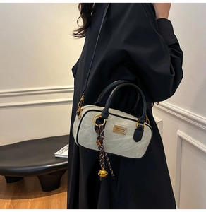 Detail of stone pattern boston bag with golden hardware and a woven bell pendant