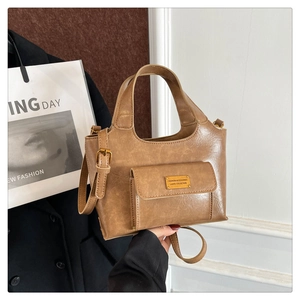 Détail du sac seau vintage en cuir marron avec plaque dorée et bandoulière ajustable