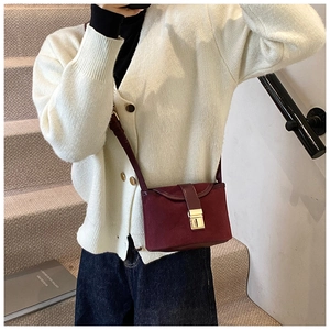 Detail of burgundy frosted leather bucket bag with gold buckle on a model at stairs